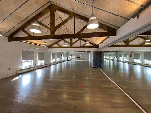 Gran salón interior con techo de vigas de madera y suelo de parquet