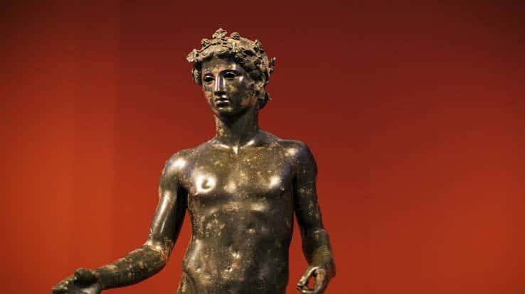 Estatua de bronce del joven de Antequera con fondo rojo