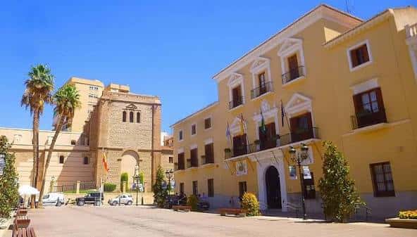 Vista panorámica de la Plaza de las Comunidades Autónomas en Motril, con edificios históricos y palmeras bajo un cielo despejado
