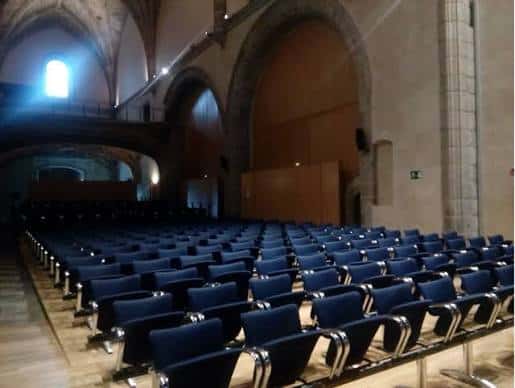 Interior del Auditorio Municipal de San Francisco con butacas azules y bóvedas góticas