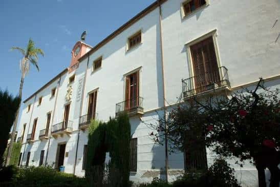 Vista lateral de la Casa de la Palma con su fachada blanca y palmera