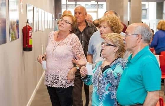 Grupo de personas mayores visitando una exposición de arte en el interior del centro