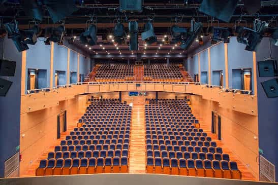 Interior del teatro desde el escenario mostrando la distribución de asientos y sistema de iluminación