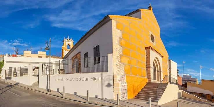 Fachada exterior del Centro Cívico San Miguel con tonos amarillos y blancos bajo cielo azul
