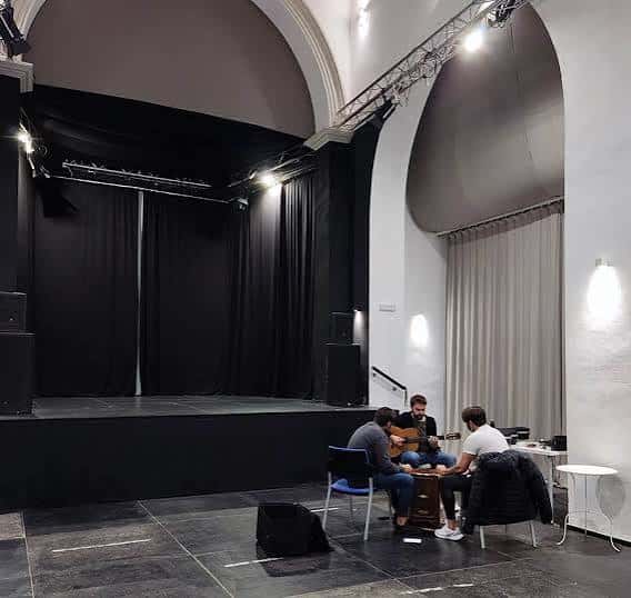 Interior del auditorio con escenario, cortinas negras y sistema de iluminación profesional
