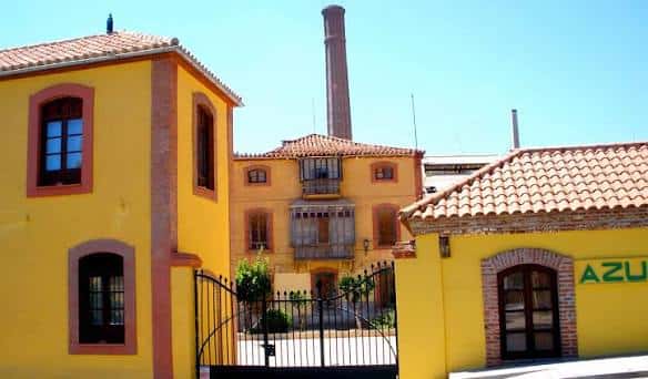 Vista exterior de la Fábrica Azucarera Nuestra Señora del Pilar con fachada amarilla y chimenea