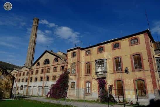 Fachada principal de la antigua fábrica con chimenea y detalles arquitectónicos