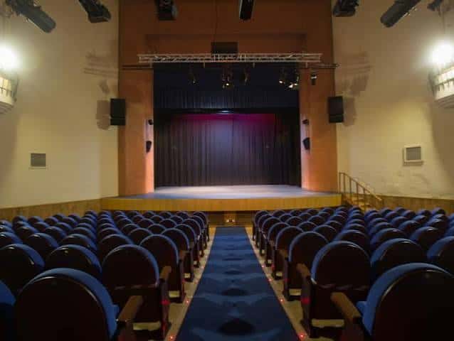 Vista frontal del auditorio con cortina roja y sistema de iluminación profesional