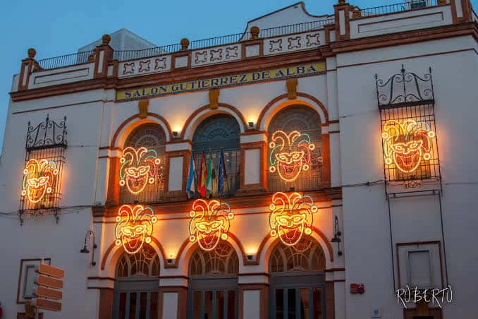 Fachada del Teatro Gutiérrez de Alba decorada con luces de carnaval y máscaras