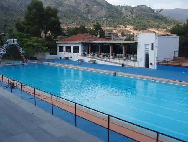 Vista lateral de la piscina olímpica con el edificio de vestuarios y el entorno montañoso