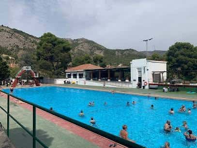Vista panorámica de la piscina con el edificio de la cafetería y las montañas de fondo