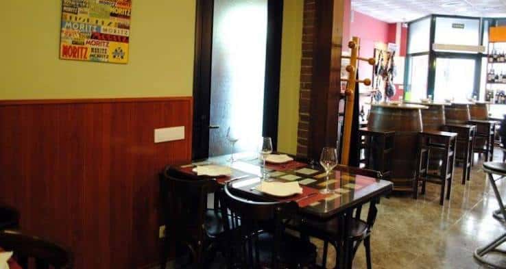 Interior del Xampu Gastrobar con mesas dispuestas y barra de madera