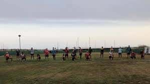 Grupo de jugadores de rugby en formación durante un entrenamiento al atardecer
