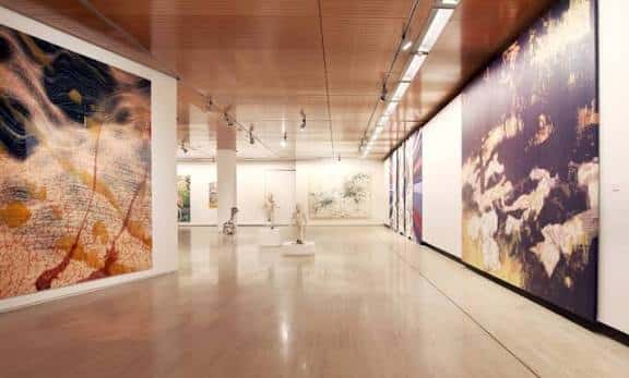 Galería principal con grandes lienzos y suelo de madera