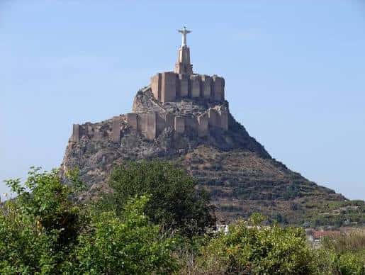 Castillo de Monteagudo desde la base, con el Cristo en la cima y vegetación en primer plano