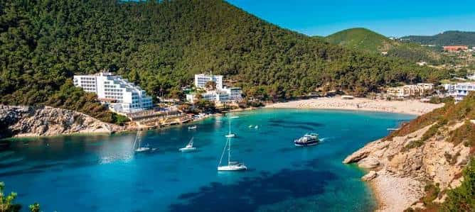 Vista aérea de la bahía de Cala Llonga con veleros y arena dorada