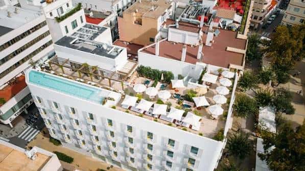 Ángulo elevado de la terraza del hotel con sombrillas, plantas y piscina integrada