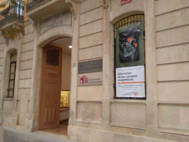 Entrada principal de la sede universitaria con cartel de exposición