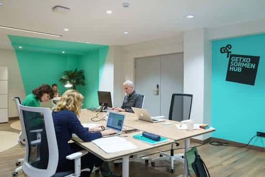 Sala de reuniones en el Getxo Sormen Hub con paredes de color turquesa y equipo de trabajo