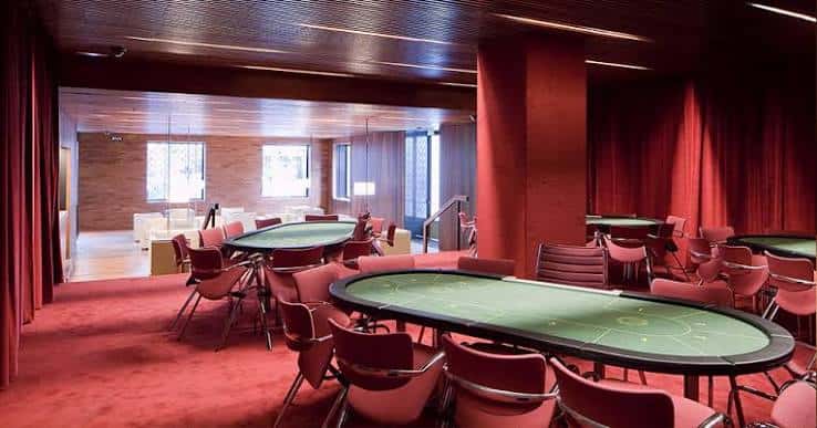 Sala de juego interior con mesas de póker y decoración en tonos rojos