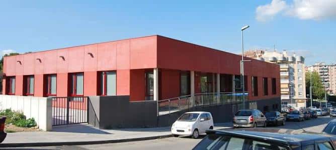 Fachada moderna del centro comunitario con paredes rojas y rampa de acceso