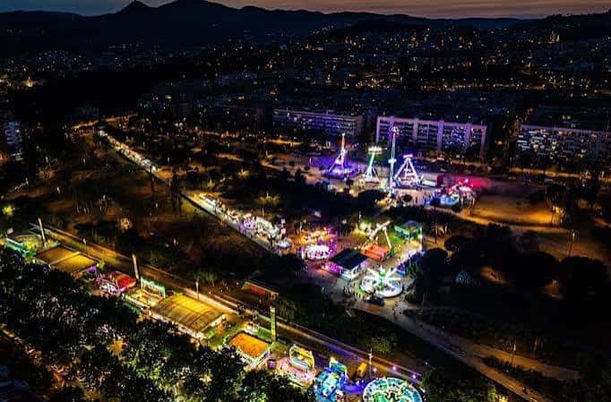 Vista nocturna aérea del Recinte Firal del Parc Central con atracciones y stands iluminados, ideal para eventos festivos o ferias