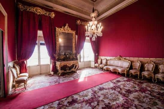 Salón de gala con decoración barroca y cortinas rojas