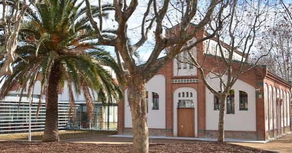 Fachada histórica del antiguo matadero con jardines y palmeras