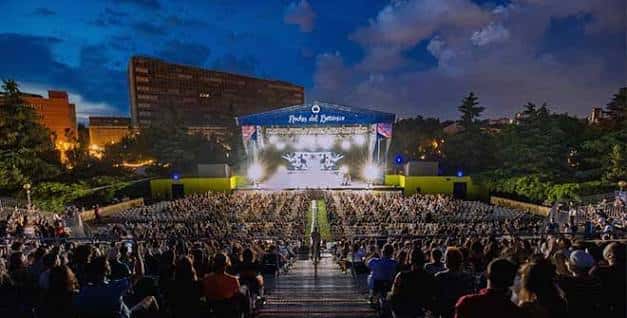 Concierto nocturno en el anfiteatro del Real Jardín Botánico con escenario iluminado y público asistente