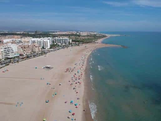 Vista aérea panorámica de la playa del Puerto de Sagunto con edificios costeros y mar azul