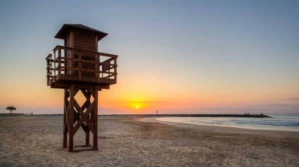 Torre de salvamento de madera al atardecer en la playa del Puerto de Sagunto