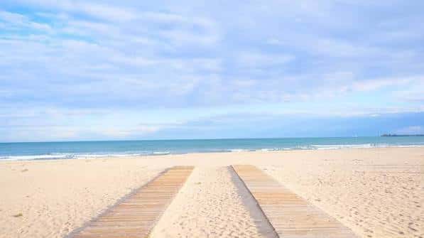 Pasarelas de madera sobre la arena hacia el mar en un día soleado
