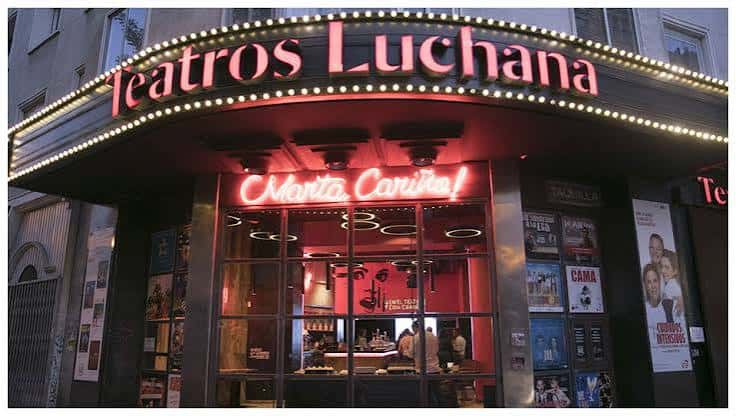 Fachada nocturna de Teatros Luchana con letrero luminoso y cartelera