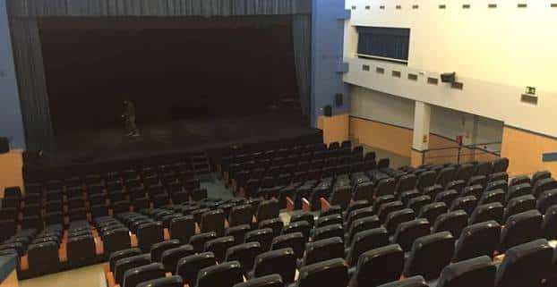 Interior del auditorio con butacas negras y escenario principal