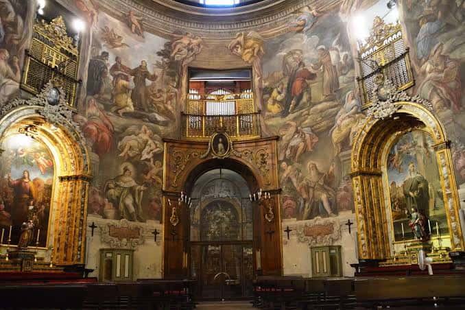 Vista interior de la nave principal con frescos en las paredes y el altar mayor