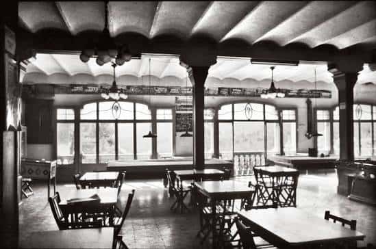 Interior histórico del salón principal con mesas y columnas
