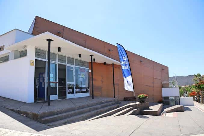 Vista exterior de la Casa de la Juventud de Adeje con fachada moderna y bandera institucional