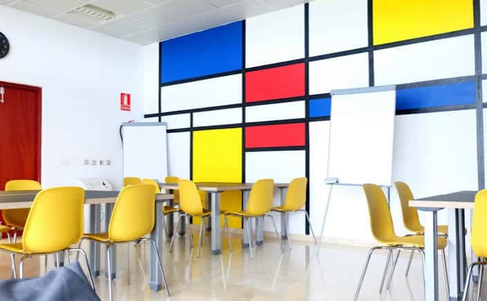 Sala interior de la Casa de la Juventud con mobiliario amarillo y pared decorativa estilo Mondrian