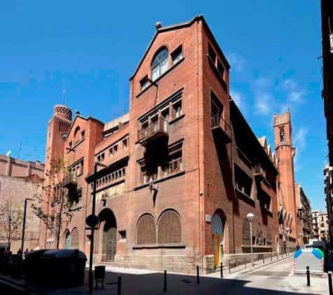 Fachada exterior de la Parròquia del Carme en Barcelona, destacando su arquitectura de ladrillo rojo y detalles modernistas