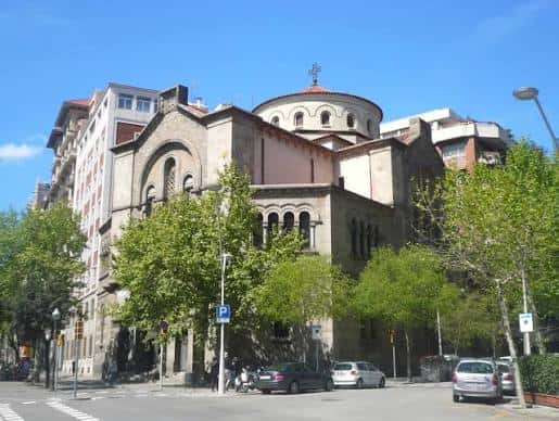 Vista exterior de la iglesia desde la calle, mostrando su cúpula y entorno urbano con árboles y tráfico