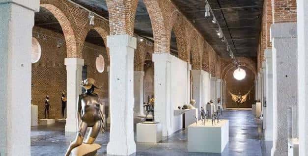 Galería de exposiciones con arcos de ladrillo y esculturas contemporáneas