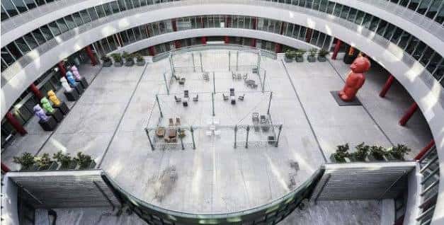 Plaza interior circular de IFEMA Madrid con mobiliario y escultura roja central
