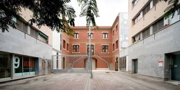 Patio central del complejo deportivo con edificio histórico de ladrillo rojo al fondo