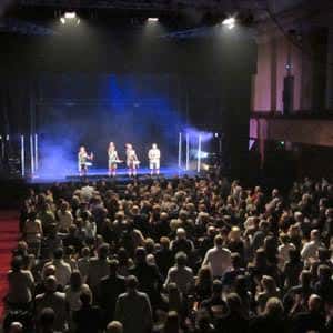 Espectáculo en vivo con público asistiendo al escenario iluminado
