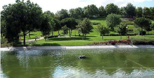 Lago del parque con personas paseando entre árboles