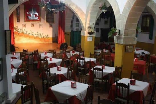 Interior de la Peña Flamenca El Chumi con mesas dispuestas para evento y escenario iluminado