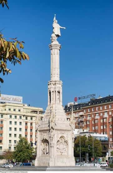Estatua monumental de Cristóbal Colón sobre su pedestal con cielo azul despejado