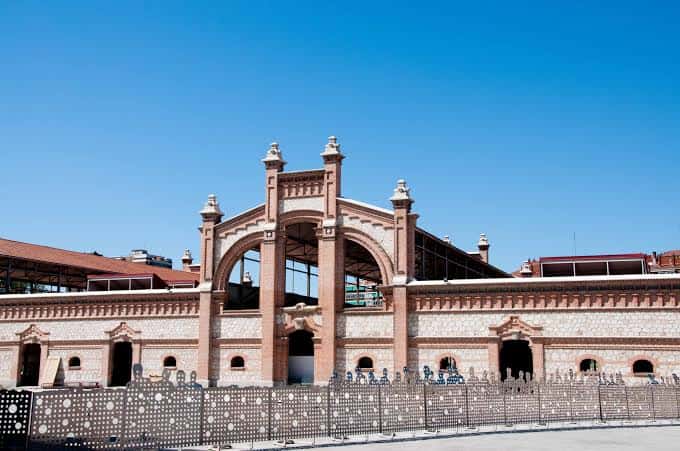 Entrada monumental del Matadero Madrid bajo cielo azul, con detalles arquitectónicos de ladrillo y piedra