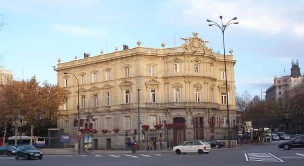 Vista general del Palacio de Linares desde la calle con banderas y tráfico urbano