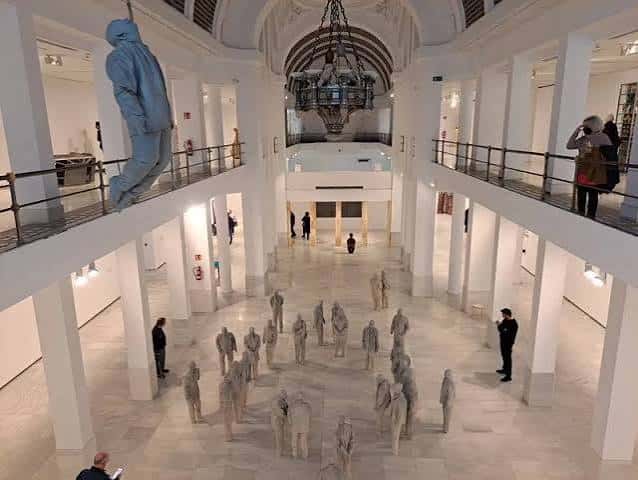 Interior del hall de la Sala Alcalá 31 con una instalación artística y visitantes recorriendo las salas